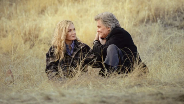Michelle Pfeiffer e Kurt Russell sentados no campo em The Madison.