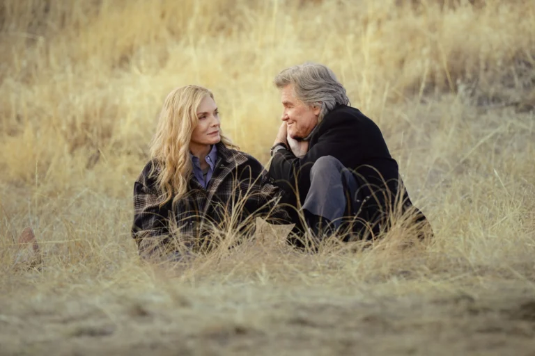 Michelle Pfeiffer e Kurt Russell sentados no campo em The Madison.