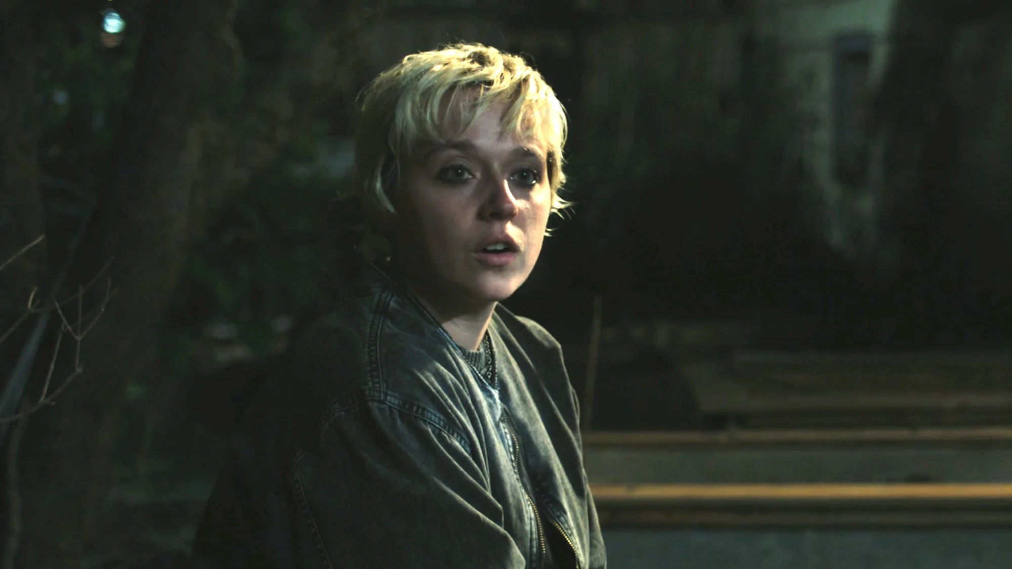 Thalia Dudek como Emaline, de cabelo curto e jaqueta, em uma cena noturna de Carrie